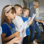 side view kids singing together sunday school